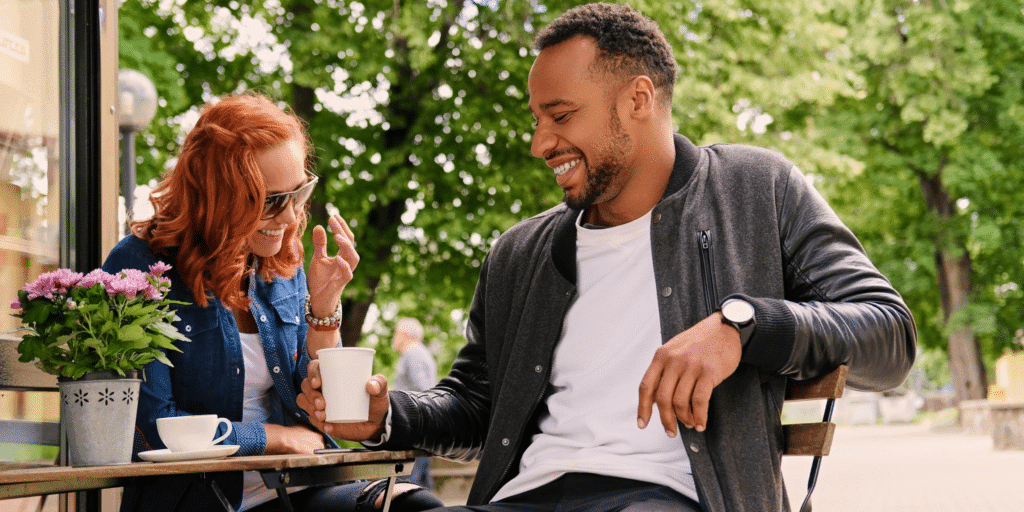 A couple laugh over coffee at a cafe showing that some people can give mixed signals when dating making it difficult to tell if they're playing hard to get or not interested in you.