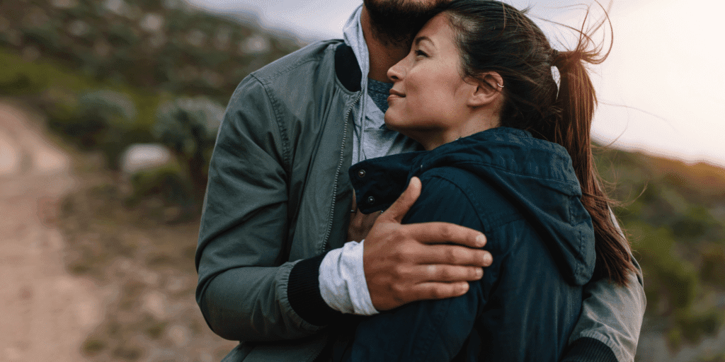 A happy couple embrace content with each other as the wind blows through their hair.