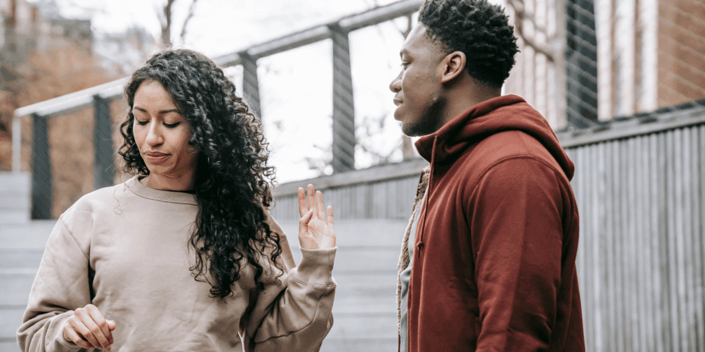 A woman holds up her hand and brushes off a man who is a serial dater.