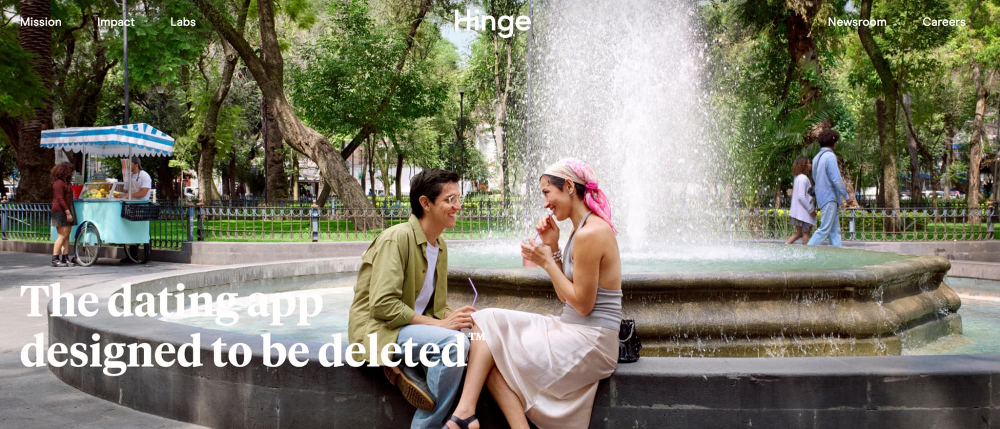 Screenshot of the Hinge website homepage showing a couple sitting by a park fountain, with the tagline "The dating app designed to be deleted."