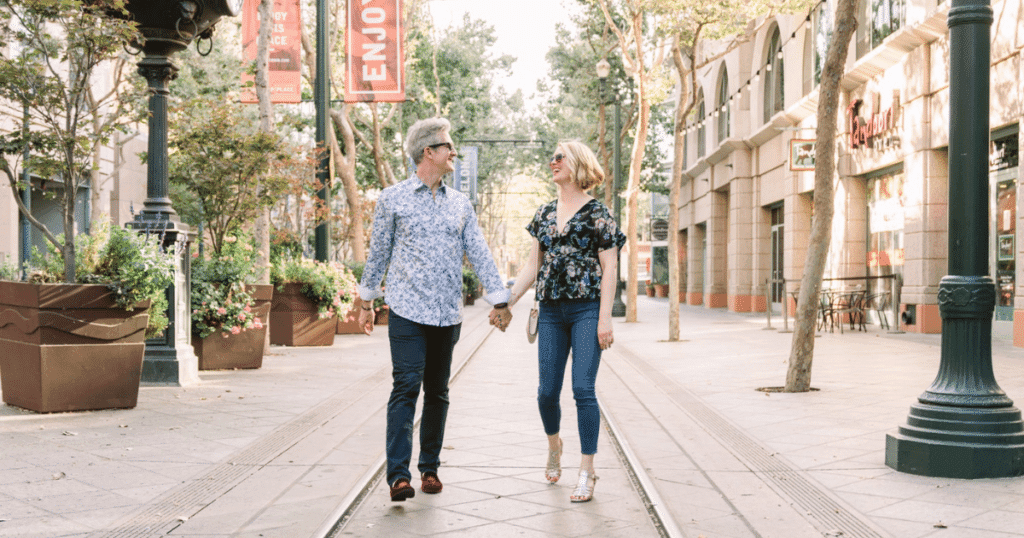 A middle-aged man and woman holding hands walking down a street market showing what PDA among couples looks like.