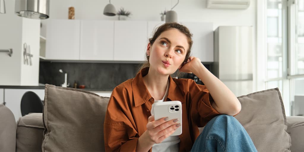 A woman sits on her couch wondering if hiring a matchmaker for her love life is worth it.